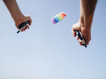 Low angle view of hand holding bottle against clear sky