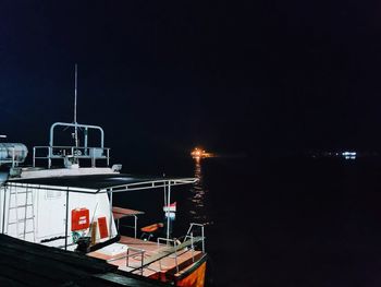 Illuminated buildings by sea against clear sky at night