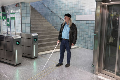 Man with white cane standing at metro station