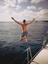 Rear view of shirtless man standing in sea against sky