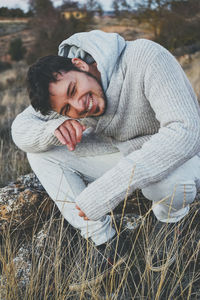 Smiling man crouching on grass during winter