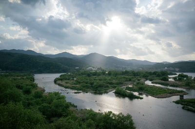 Scenic view of river by mountains against sky