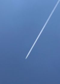 Low angle view of airplane flying against blue sky