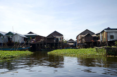 Houses by lake against sky