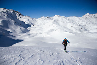 Woman skiing on snowcapped mountain against sky