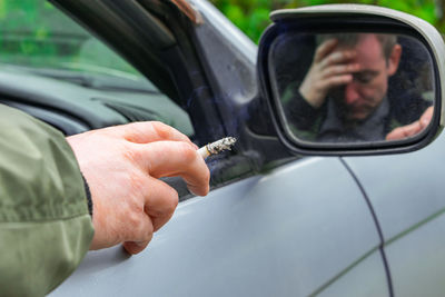 Reflection of man on side-view mirror of car