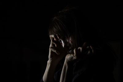 Portrait of young woman with halloween make-up against black background