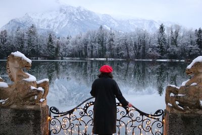 Rear view of woman standing by railing against lake