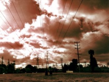 Electricity pylon against cloudy sky