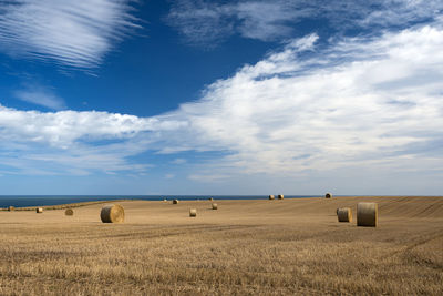 Hay bales on field against sky