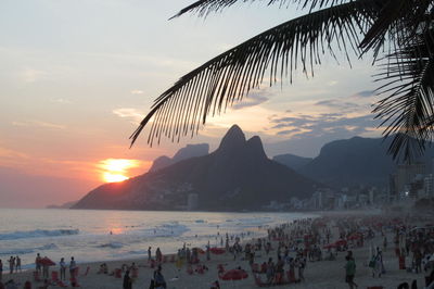 People enjoying vacation at beach with mountain in background during sunset