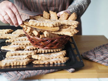  the hands of an elderly woman remove the prepared freshly baked cookies from the baking sheet 