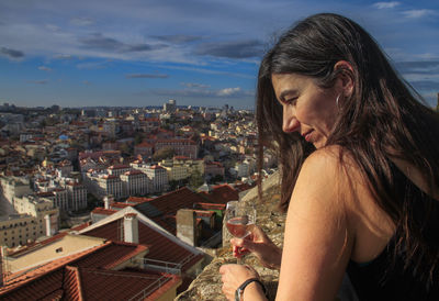 Rear view of woman standing against buildings in city