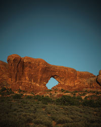 Rock formations on landscape against clear blue sky