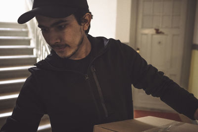 Confident delivery man with package making home delivery