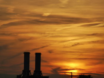 Smoke stacks against sky during sunset