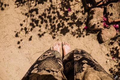 Low section of woman standing on sand at beach