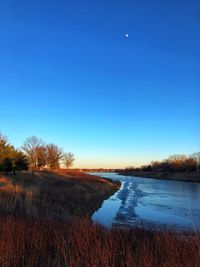 Scenic view of lake against clear blue sky