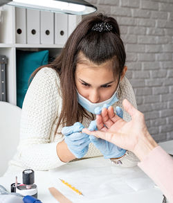 Young woman wearing glove and mask working at salon