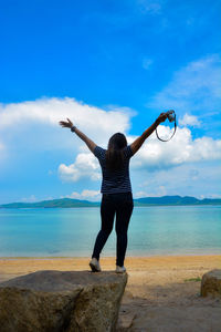 Rear view of woman standing at sea shore against sky