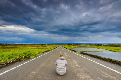 Road amidst field against sky