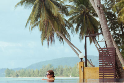 Woman swimming in pool at beach against sky