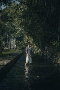 Full length of young man standing in forest