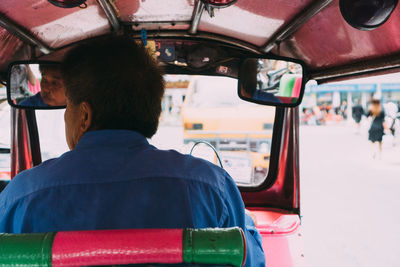 Rear view of man driving car in city