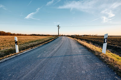 Road amidst field against sky