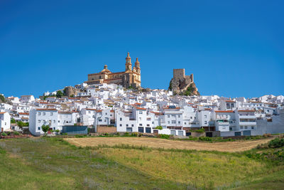 Buildings in city against clear blue sky