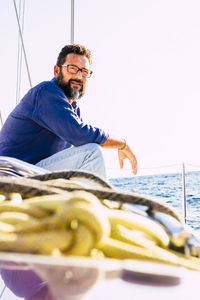 Portrait of young man sitting on boat against sea