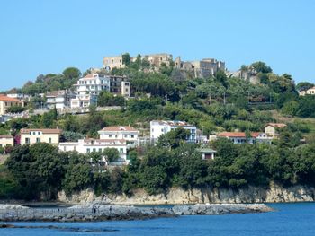 View of townscape by sea against clear blue sky