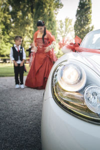 Bride with boy standing by car on road