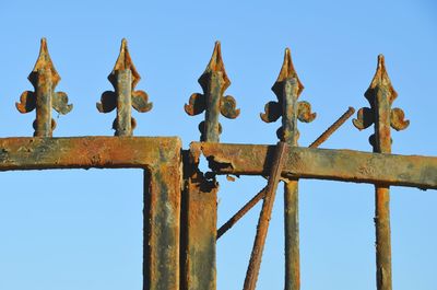 Low angle view of rusty fence against sky 