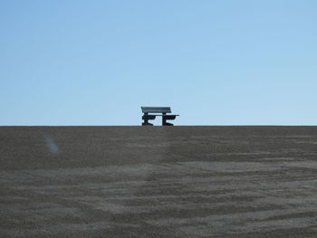 Lifeguard hut on land against clear blue sky