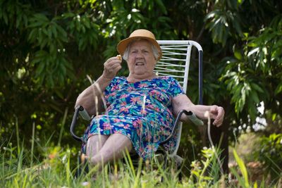 Full length of woman sitting on chair against trees