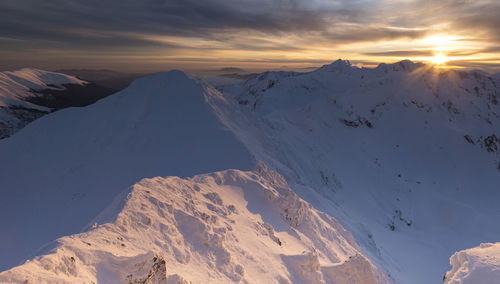 Scenic view of snow covered mountains against sky during sunset