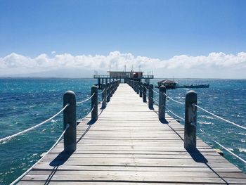 Pier over sea against blue sky