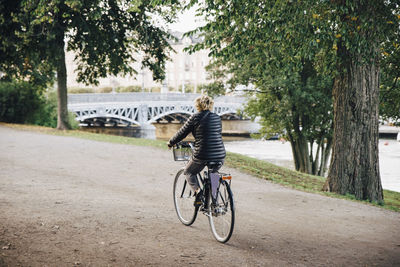 Full length rear view of senior woman riding bicycle in park