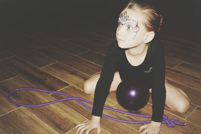 Girl with face paint sitting on floor at home