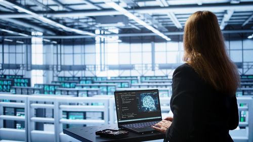 Rear view of woman using laptop at office