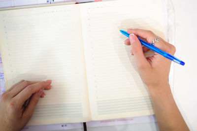 Cropped hands of woman writing on book with pen