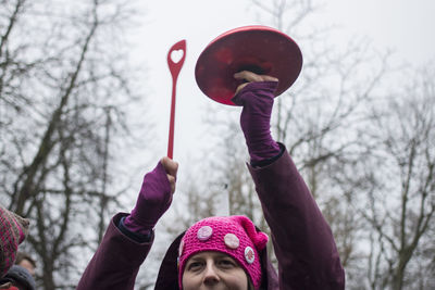 Close-up of hand holding balloons against bare trees