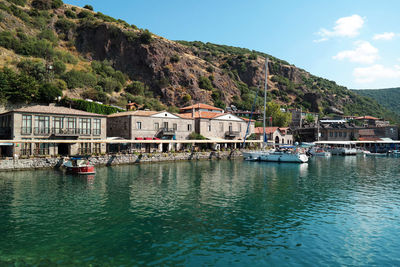 Scenic view of sea by buildings and mountains against sky