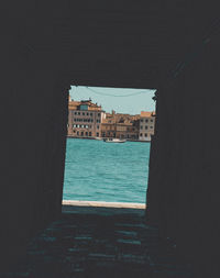 Buildings by sea against clear sky