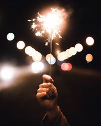 Cropped hand holding illuminated sparkler