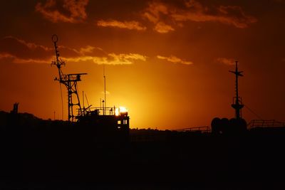 Silhouette of communications tower against sky during sunset