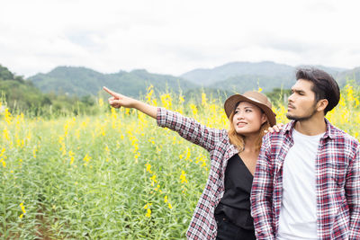 Young couple standing by plants against sky