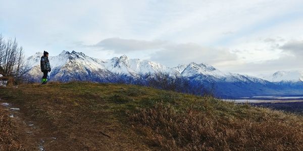 Girl looking away standing against snowcapped mountains 