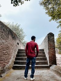 Rear view of man standing on staircase against building